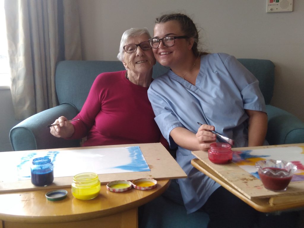 Resident and care assistant enjoying arts and crafts