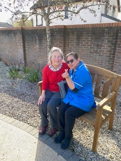 A resident and staff member on a bench