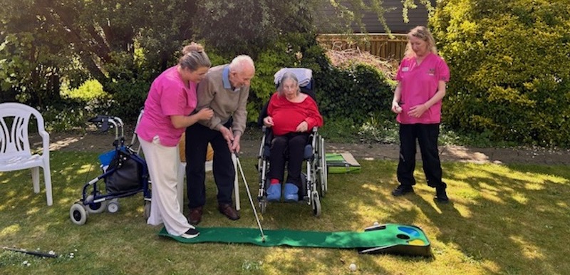 resident playing garden golf with help of our team