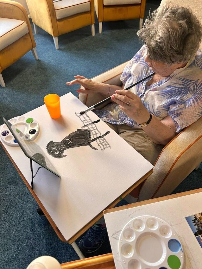 one of our residents sat painting a dog on a canvas