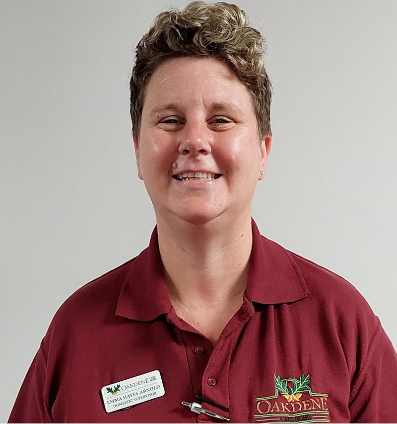 female domestic supervisor with blonde hair in a red uniform smiling for her team photo
