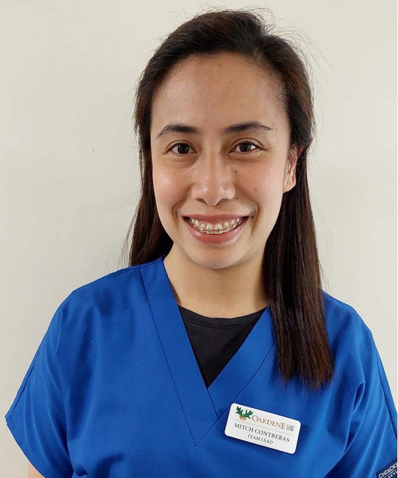 female team leader with brown hair in a blue uniform smiling for her team photo