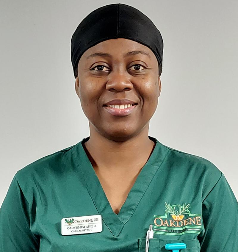 female care assistant wearing a green uniform smiling for a team photo
