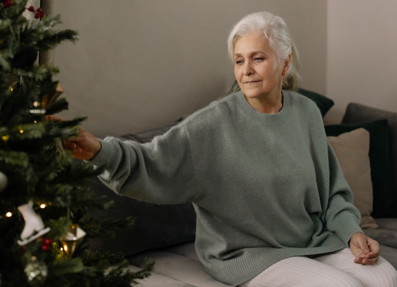 older woman sitting looking at a christmas tree