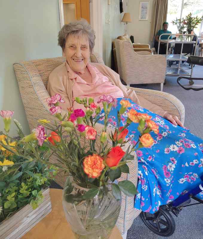 resident sitting behind a bouquet of flowers